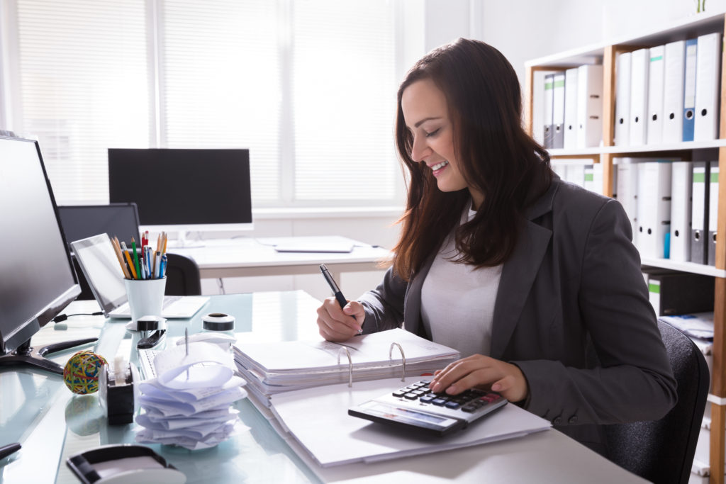 Happy Young Businesswoman Calculating Bill With Calculator